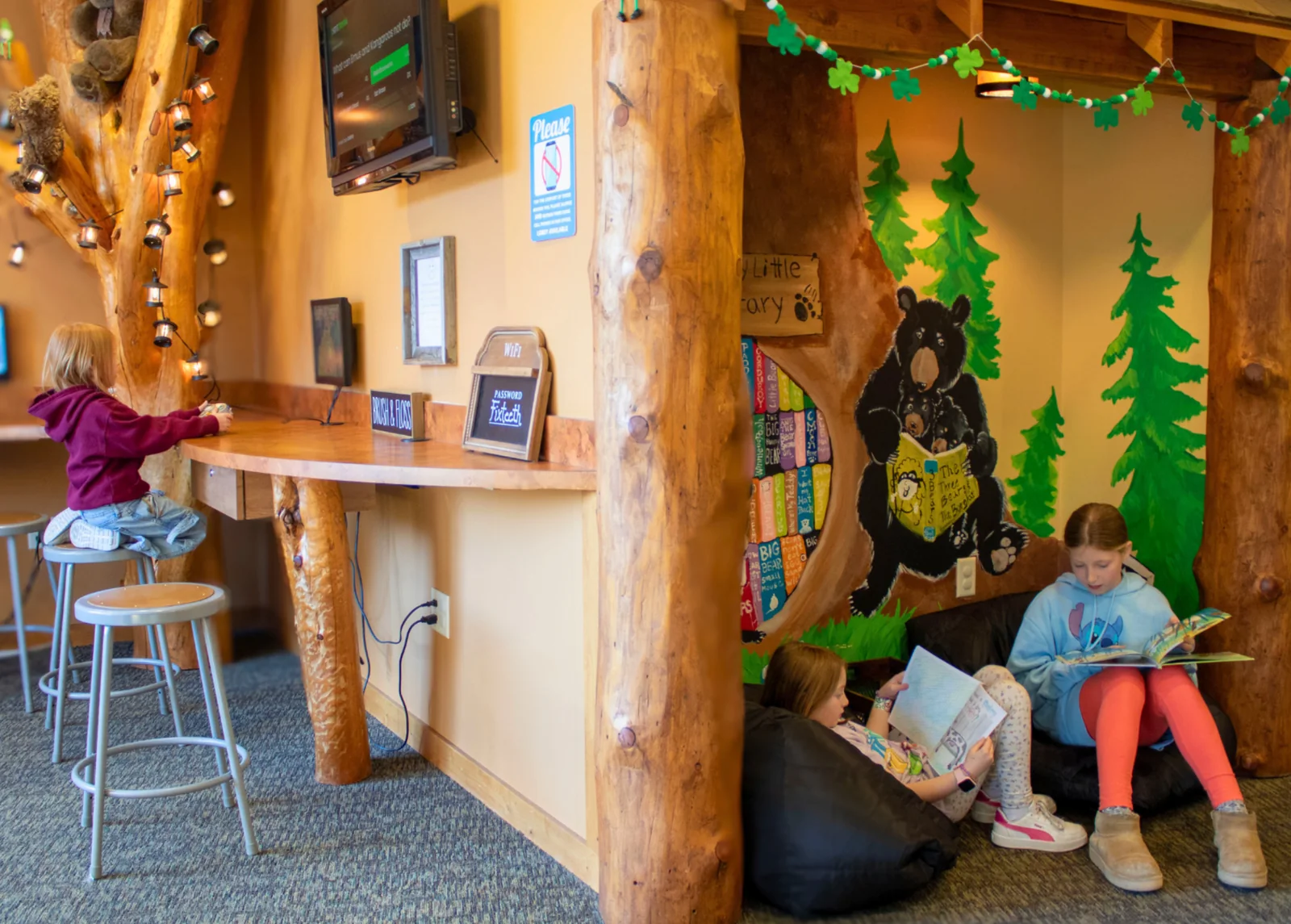 Children reading beside the bear mural in The Kidds Place waiting area
