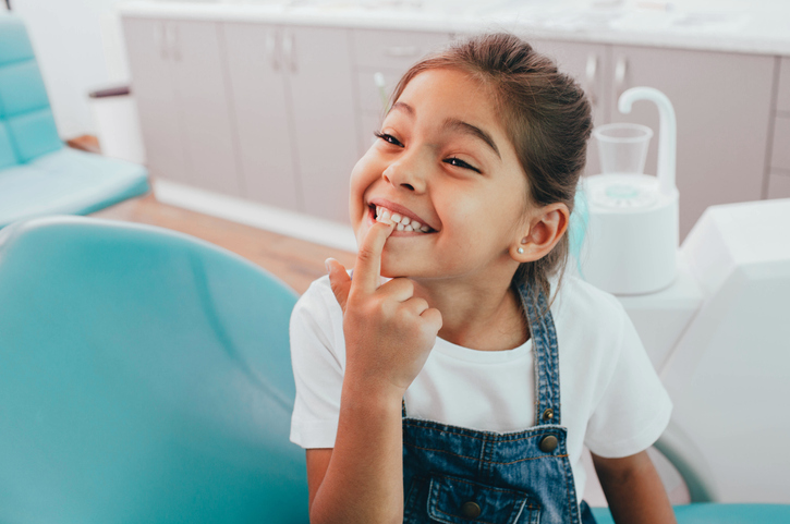 Smiling dark-haired child at the dentist's office after her dental sealant visit.